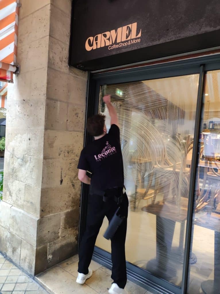 Salarié Leconte Nettoyage nettoyant une vitrine à Bordeaux lors d’une intervention de lavage de vitres.