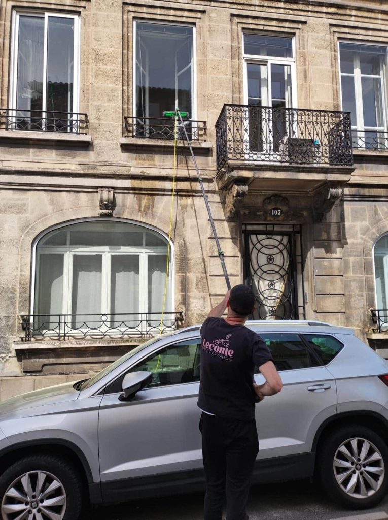 Employé Leconte Nettoyage effectuant le lavage des vitres grâce à une perche à Bordeaux.