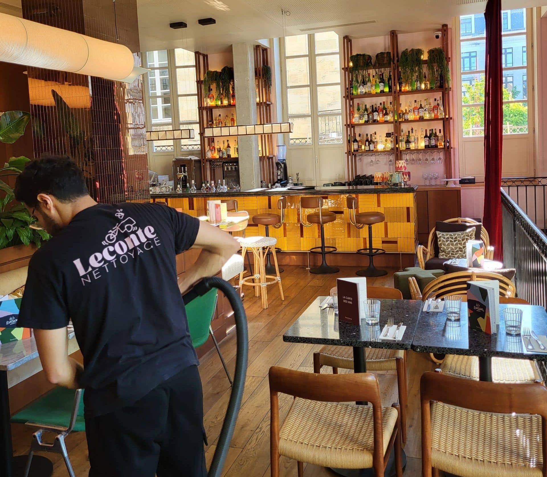 Employé de l’entreprise Leconte Nettoyage effectuant l’entretien régulier des locaux du restaurant French House à Bordeaux, vu de dos en train de passer l’aspirateur.