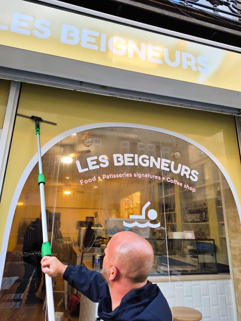 Employé Leconte Nettoyage nettoyant la vitrine du magasin Les Beigneurs à Bordeaux.
