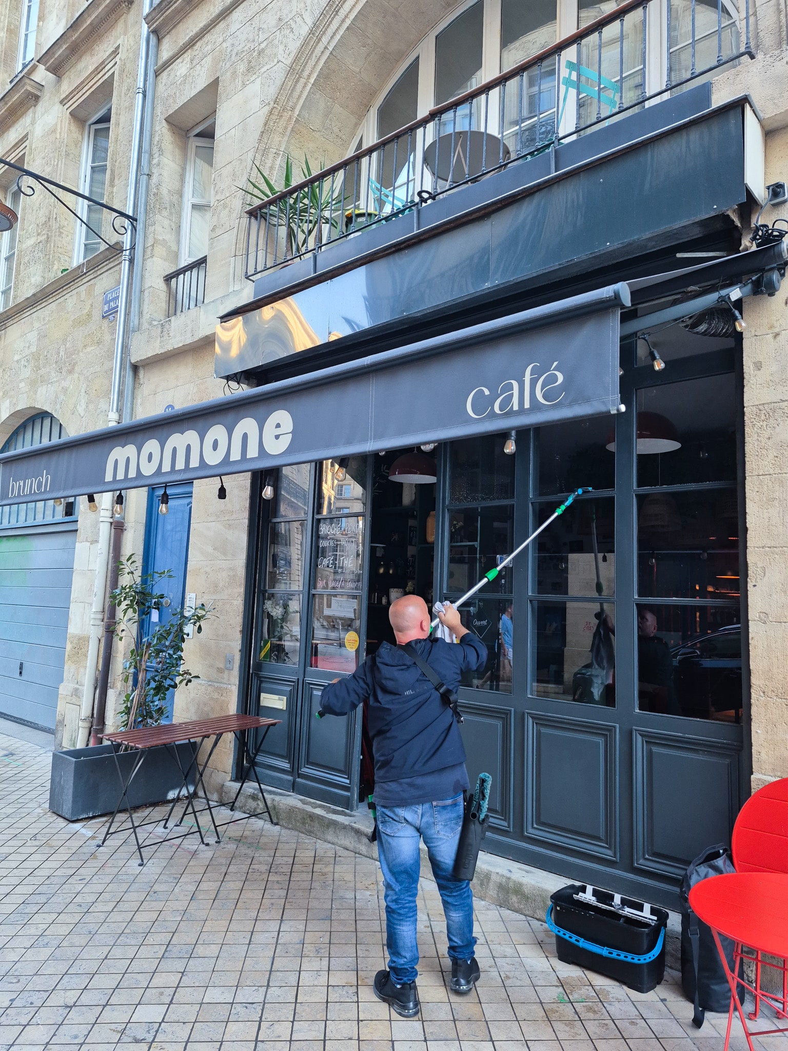 Salarié Leconte Nettoyage effectuant le nettoyage des vitres du restaurant Momone à Bordeaux.